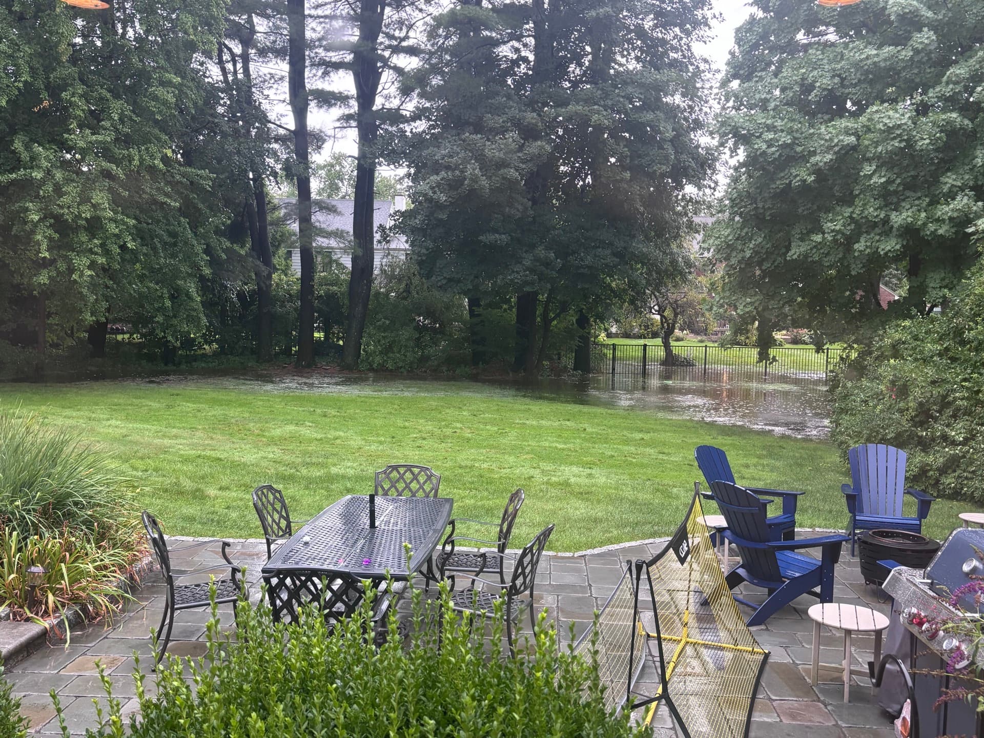 Flooded backyard during a Connecticut storm, standing water pooling near a fence line